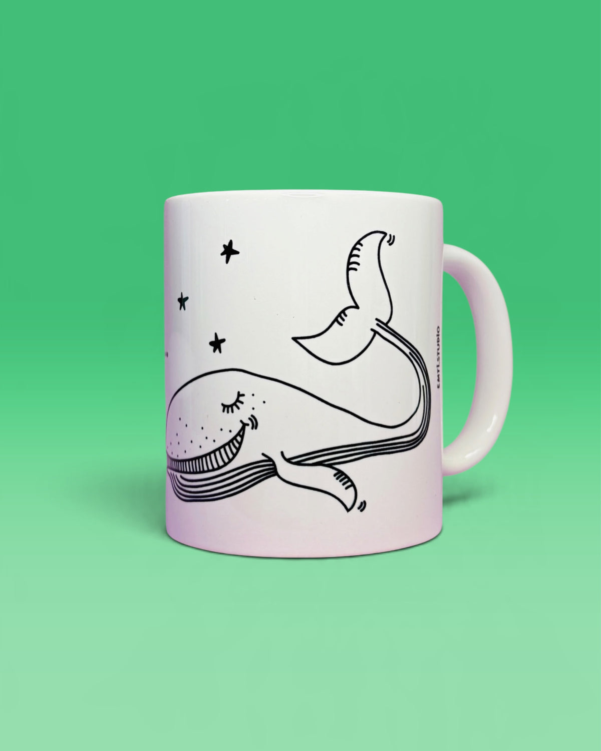 Weisse Tasse mit einem gezeichneten Wal zwischen Sternen