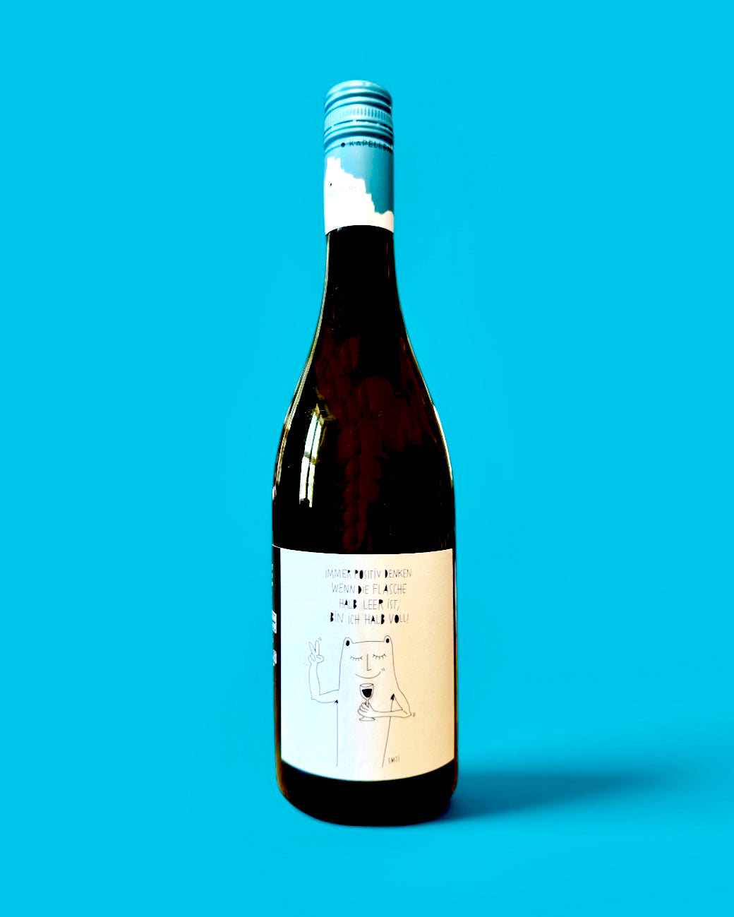 Weinflasche vor türkisem Grund, Etikett „Vino Wisdom“ von Jean Rapp und EMTI, schwarz-weiße Zeichnung: eine Figur mit Weinglas zeigt das Peace-Zeichen, dazu „Immer positiv denken: wenn die Flasche halb leer ist, bin ich halb voll!“