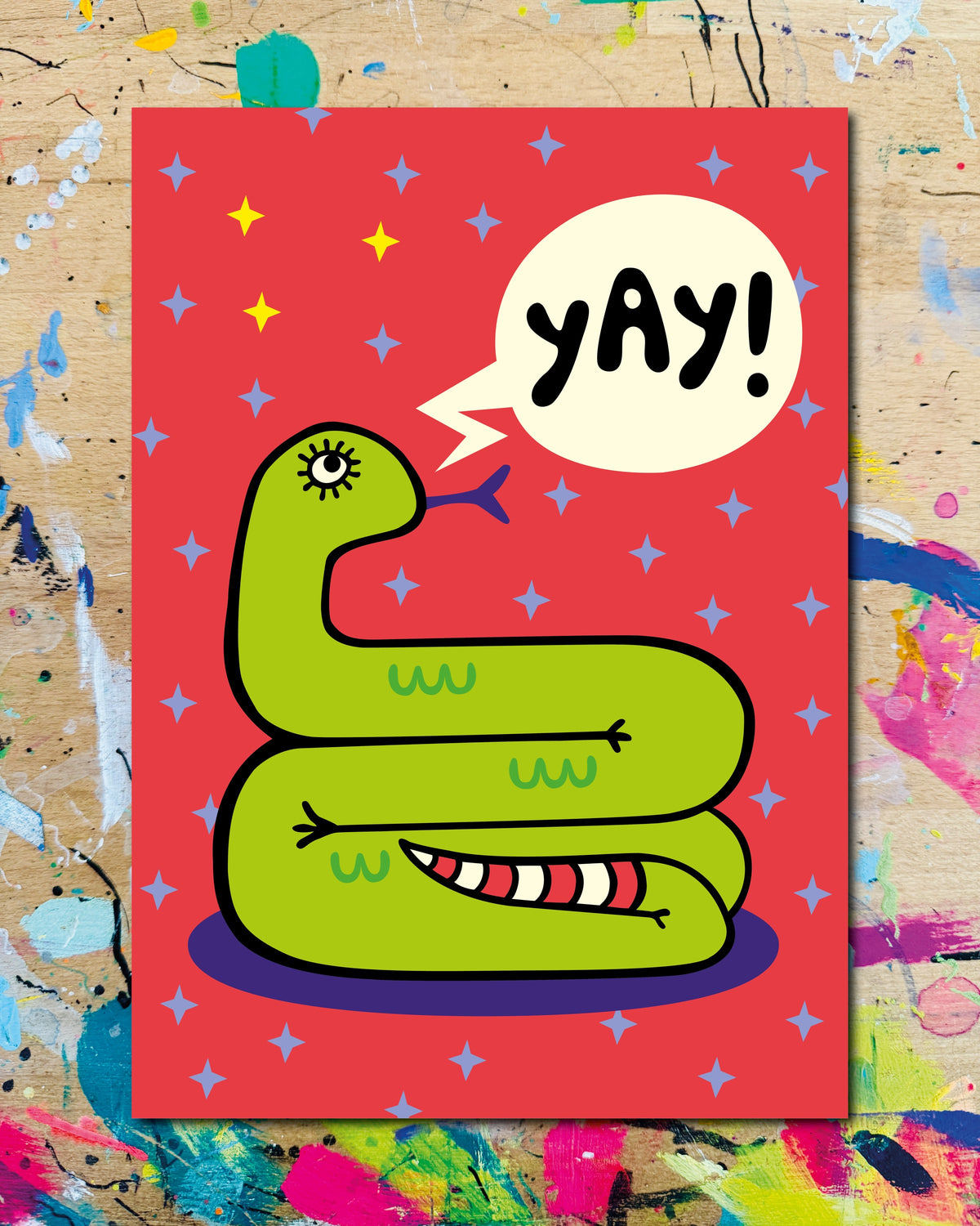 Postkarte: eine zusammengerollte grüne Schlange auf rotem Grund, dazu der Schriftzug „Yay!“