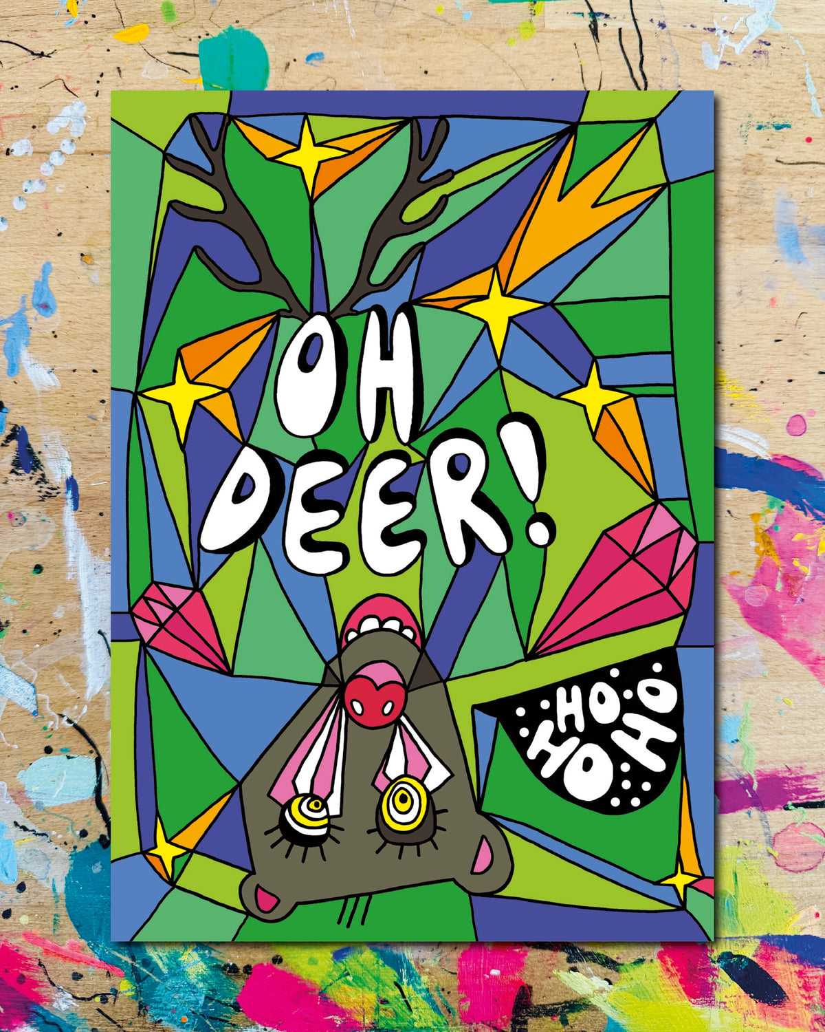 Postkarte: ein Rentier mit roter Nase schaut kopfüber und mit offenem Maul ins Bild, auf grün-blauem Grund mit Sternen, dazu die Schriftzüge „Oh Deer!“ und „Ho ho ho“