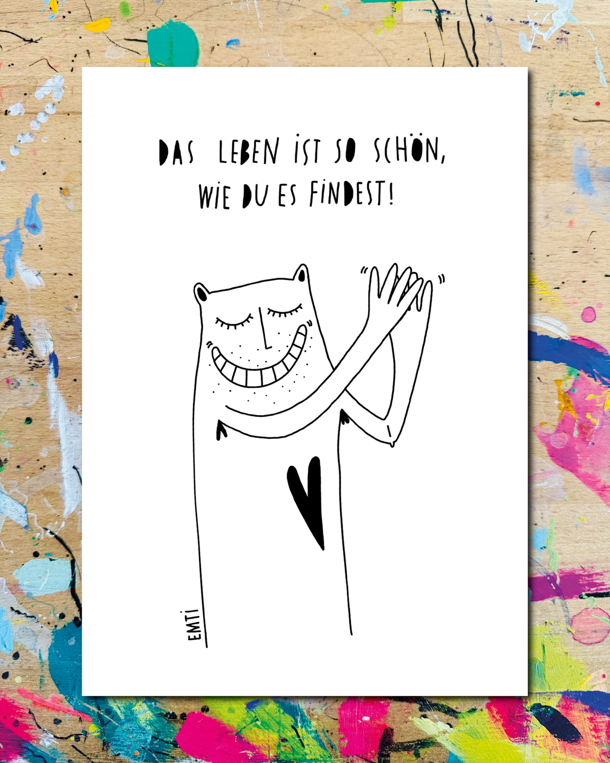 Postkarte: eine breit grinsende Figur klatscht in die Hände, dazu der Schriftzug „Das Leben ist so schön, wie du es findest!“
