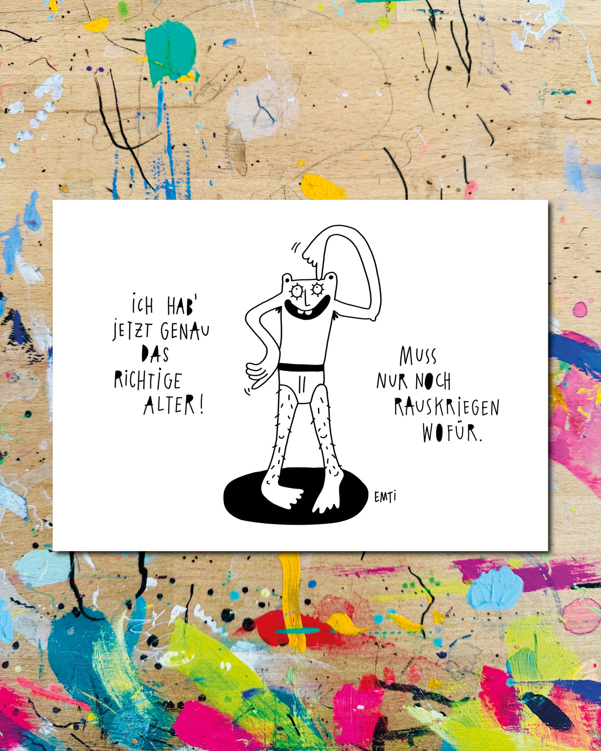 Postkarte quer: eine Figur in Badehose auf einem schwarzen Fleck, dazu der Schriftzug „Ich hab jetzt genau das richtige Alter! Muss nur noch rauskriegen wofür.“