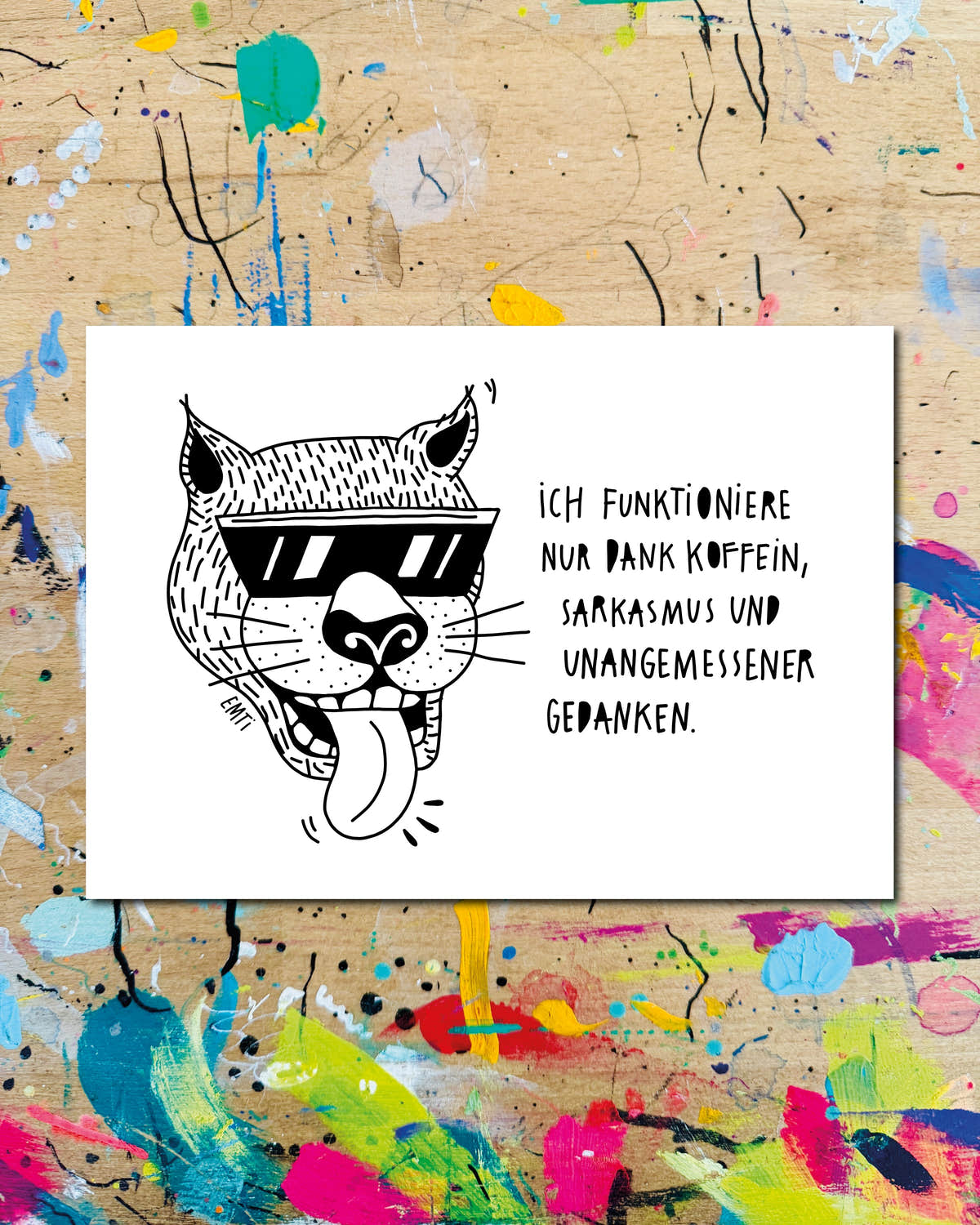 Postkarte quer: ein Katzenkopf mit Sonnenbrille und herausgestreckter Zunge, dazu der Schriftzug „Ich funktioniere nur dank Koffein, Sarkasmus und unangemessener Gedanken.“