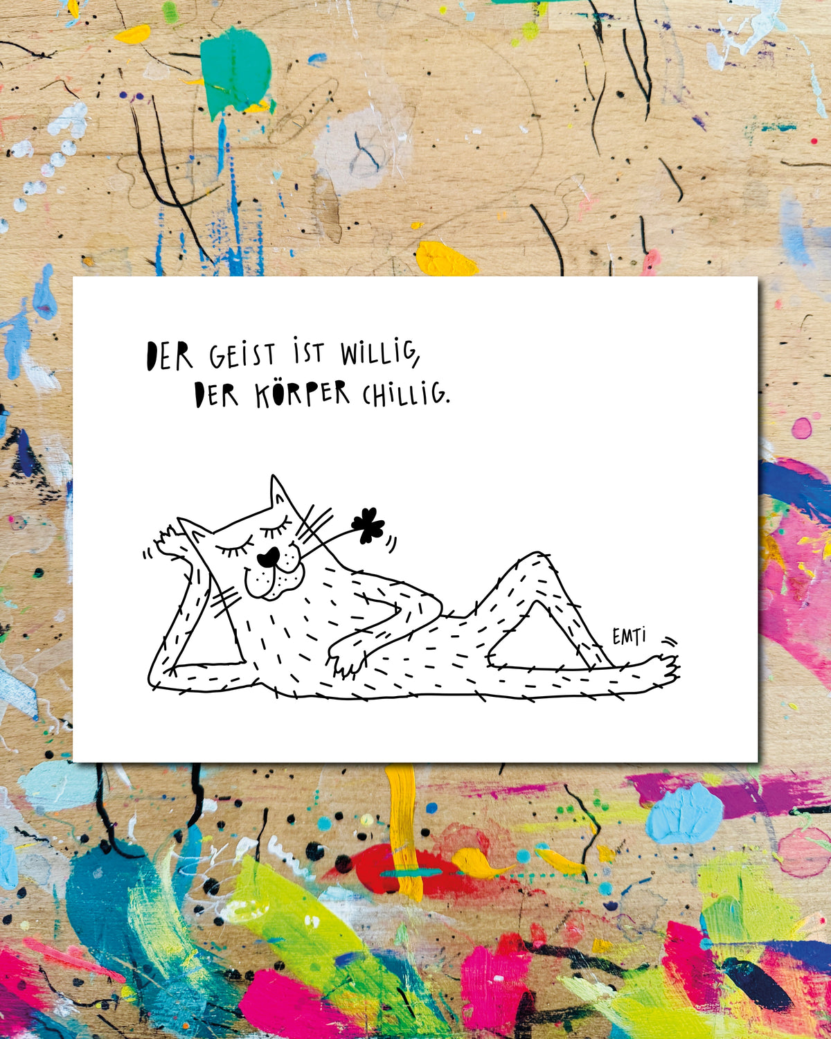Postkarte quer: eine Katze liegt entspannt auf der Seite, dazu der Schriftzug „Der Geist ist willig, der Körper chillig.“