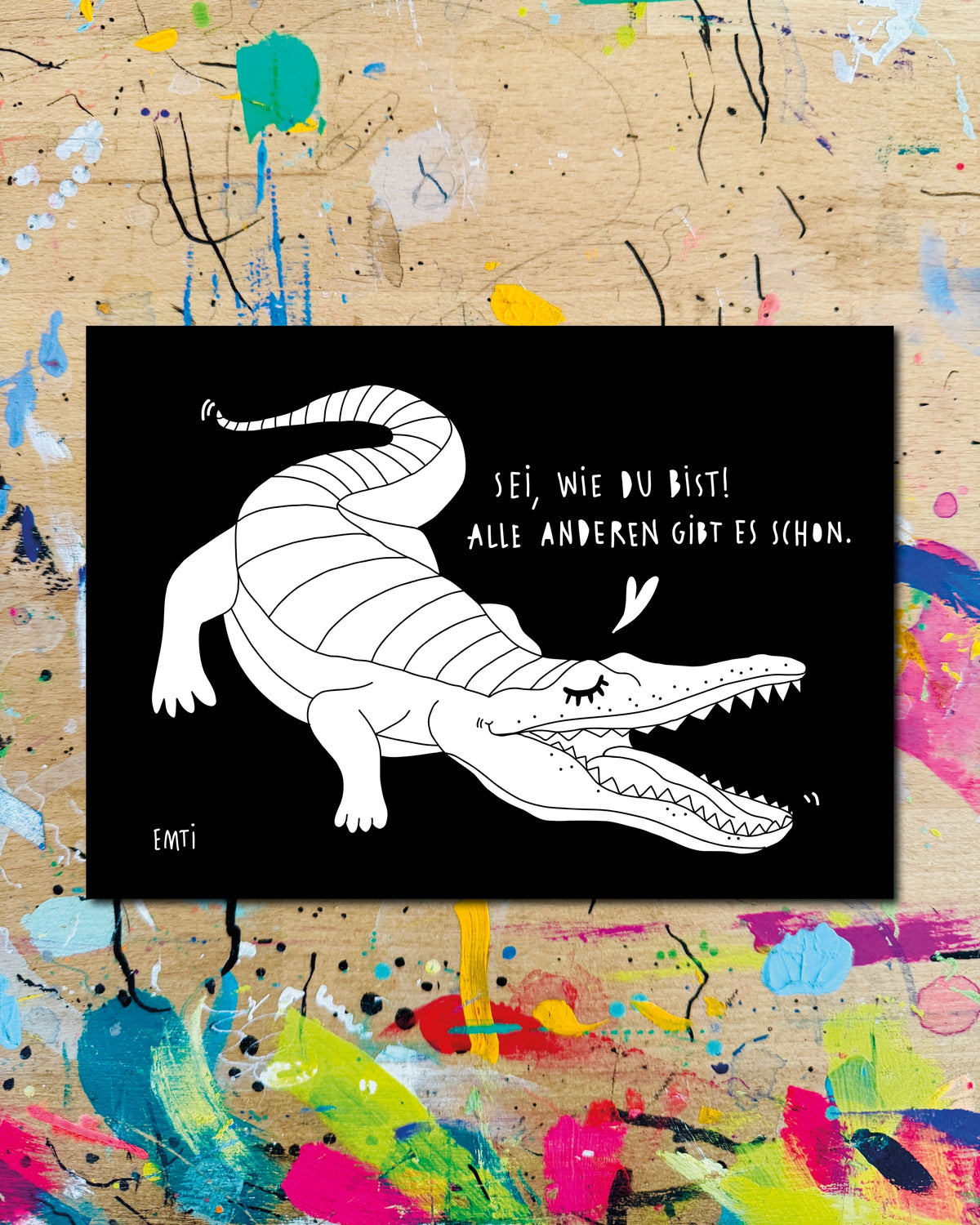 Postkarte quer: ein Krokodil mit Herz auf schwarzem Grund, dazu der Schriftzug „Sei, wie du bist! Alle anderen gibt es schon.“