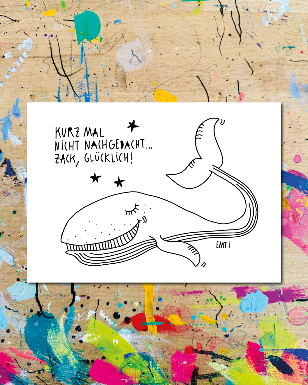Postkarte quer: ein lächelnder Wal zwischen Sternen, dazu der Schriftzug „Kurz mal nicht nachgedacht… zack, glücklich!“