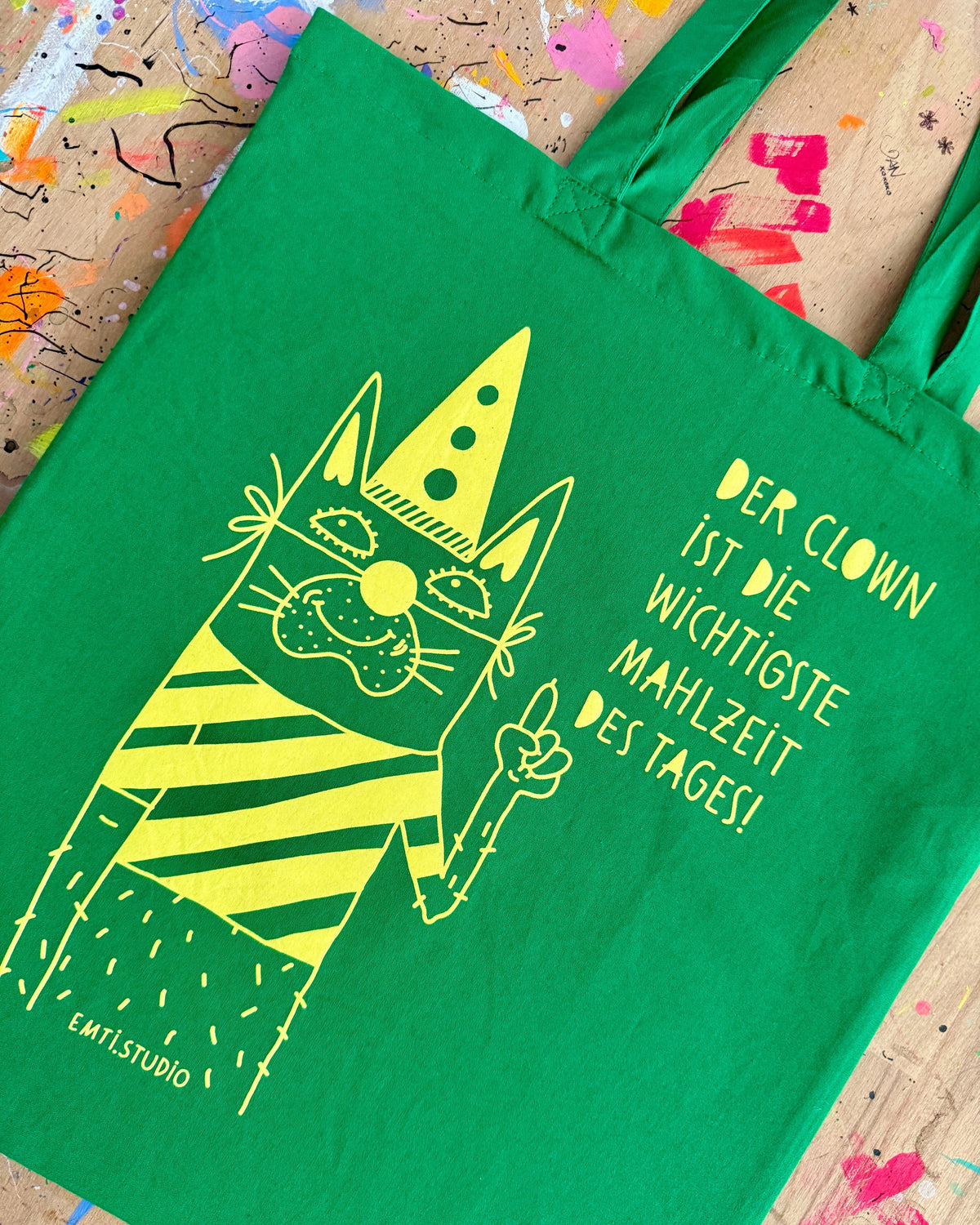 Grüner Stoffbeutel mit einer gezeichneten Katze mit Partyhut und dem Schriftzug „Der Clown ist die wichtigste Mahlzeit des Tages!“