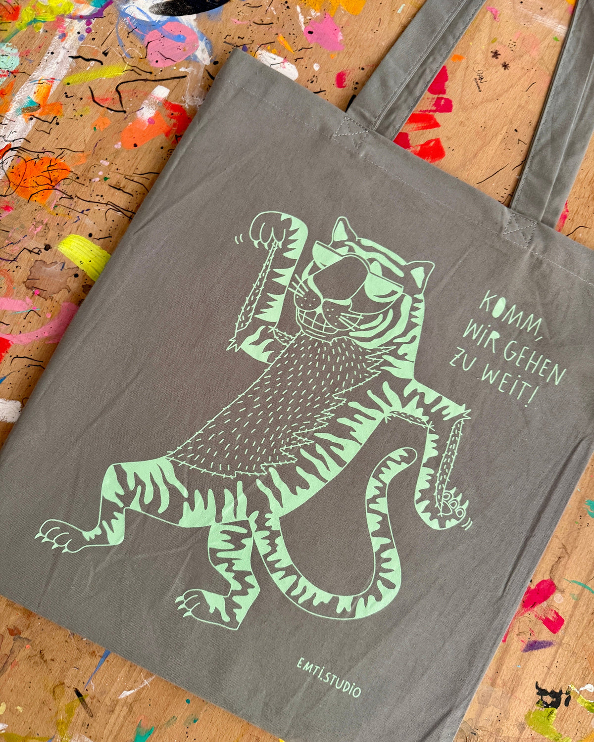 Grauer Stoffbeutel mit einem gezeichneten Tiger und dem Schriftzug „Komm, wir gehen zu weit!“
