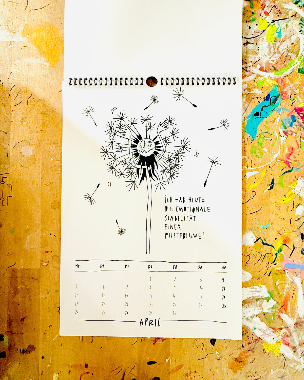 Kalenderblatt April: eine Pusteblume mit Gesicht, deren Schirmchen davonfliegen, dazu „Ich hab’ heute die emotionale Stabilität einer Pusteblume!“